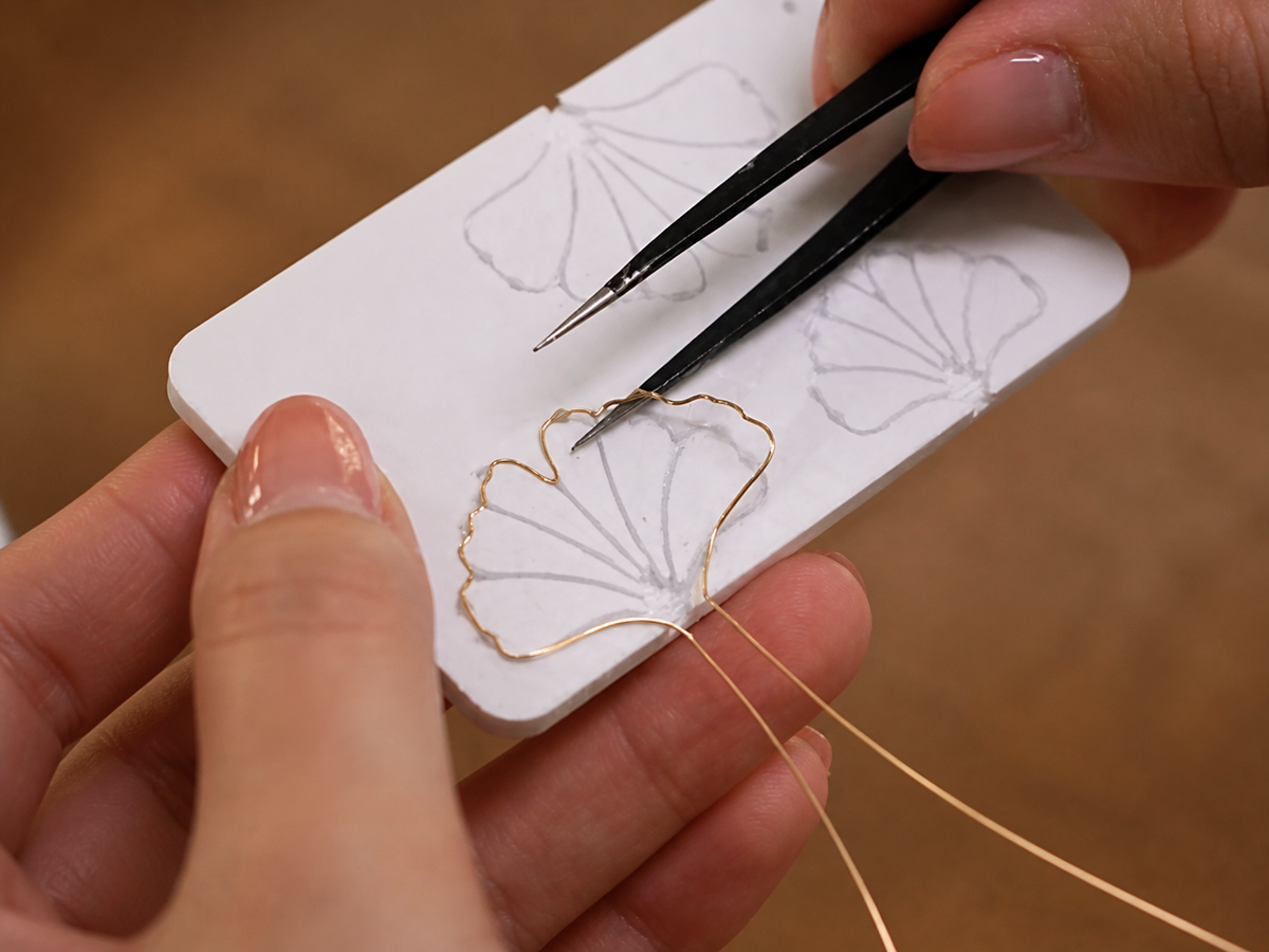 Artisan bending fine wire to a floral template for Ronghua